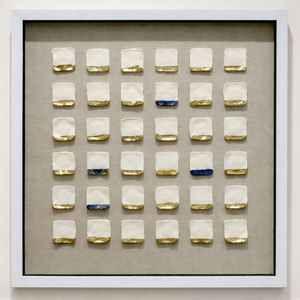 Framed artwork with square tiles featuring gold and blue accents on a beige background